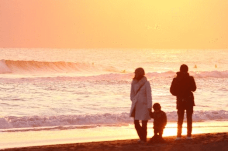 夕日の海辺を歩く親子
