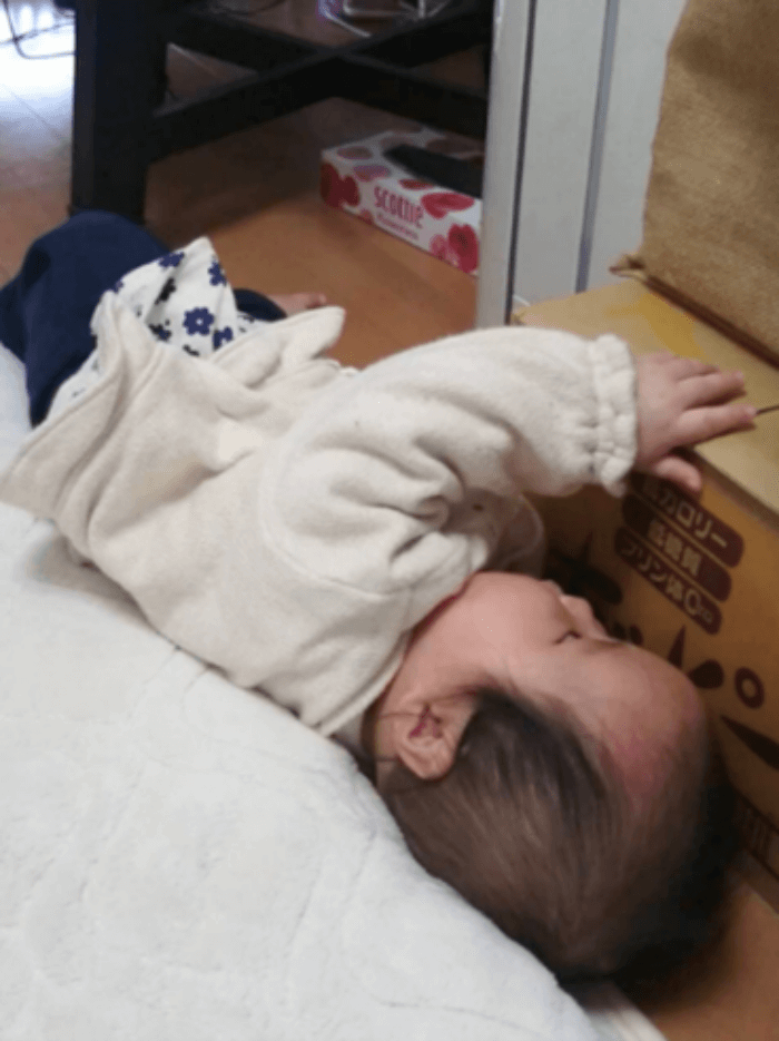 布団とダンボールに挟まる子ども